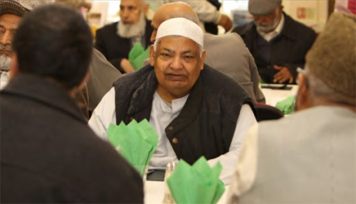 Elderly Asian man seated at communal dining table