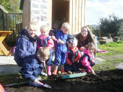 Young children digging with trowels with two young mums