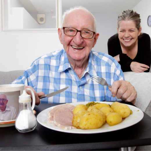 Older man eating lunch with young woman behind